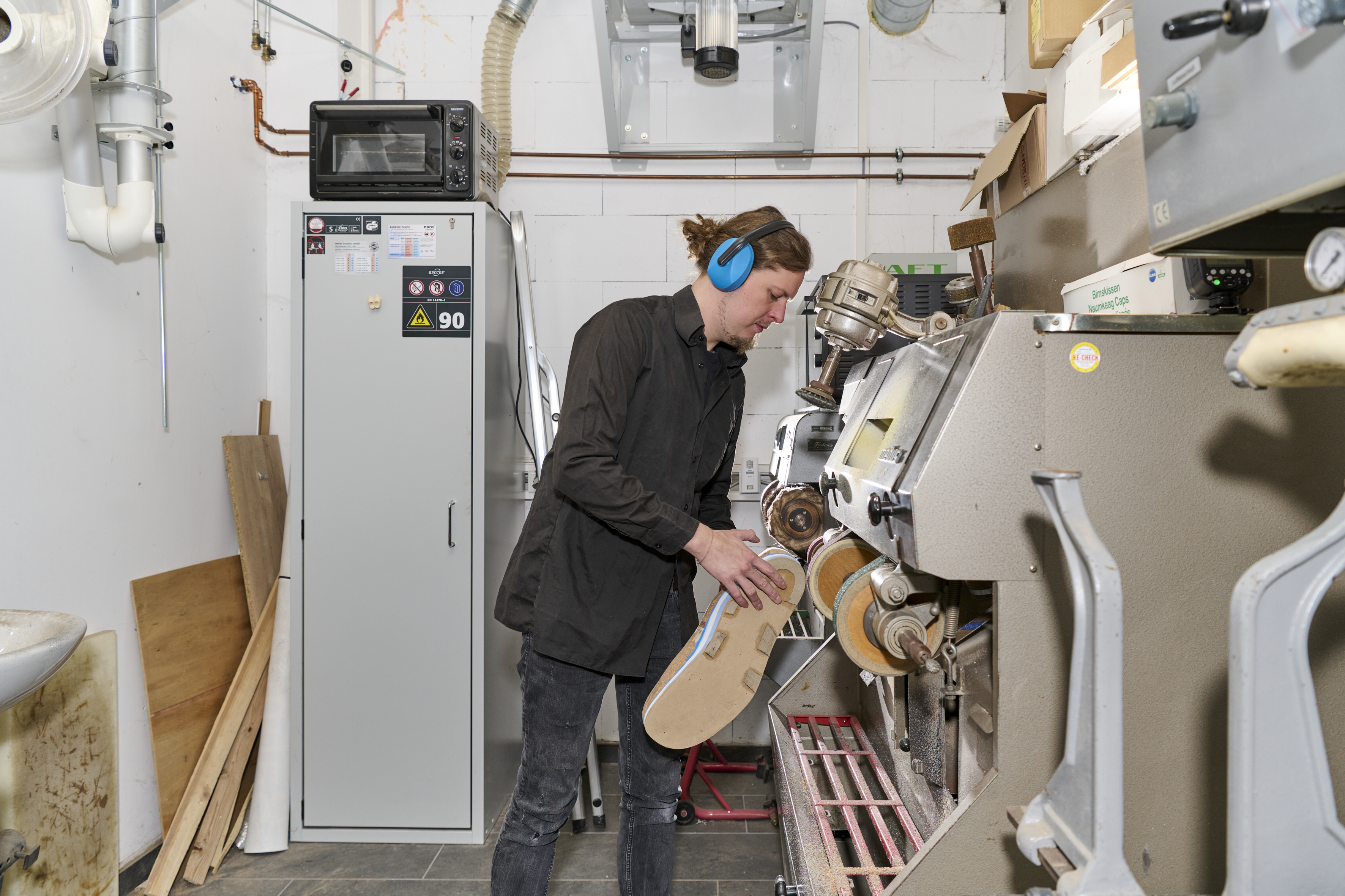 Adrian Wessels bearbeitet einen Schuh an einer Schleifmaschine.