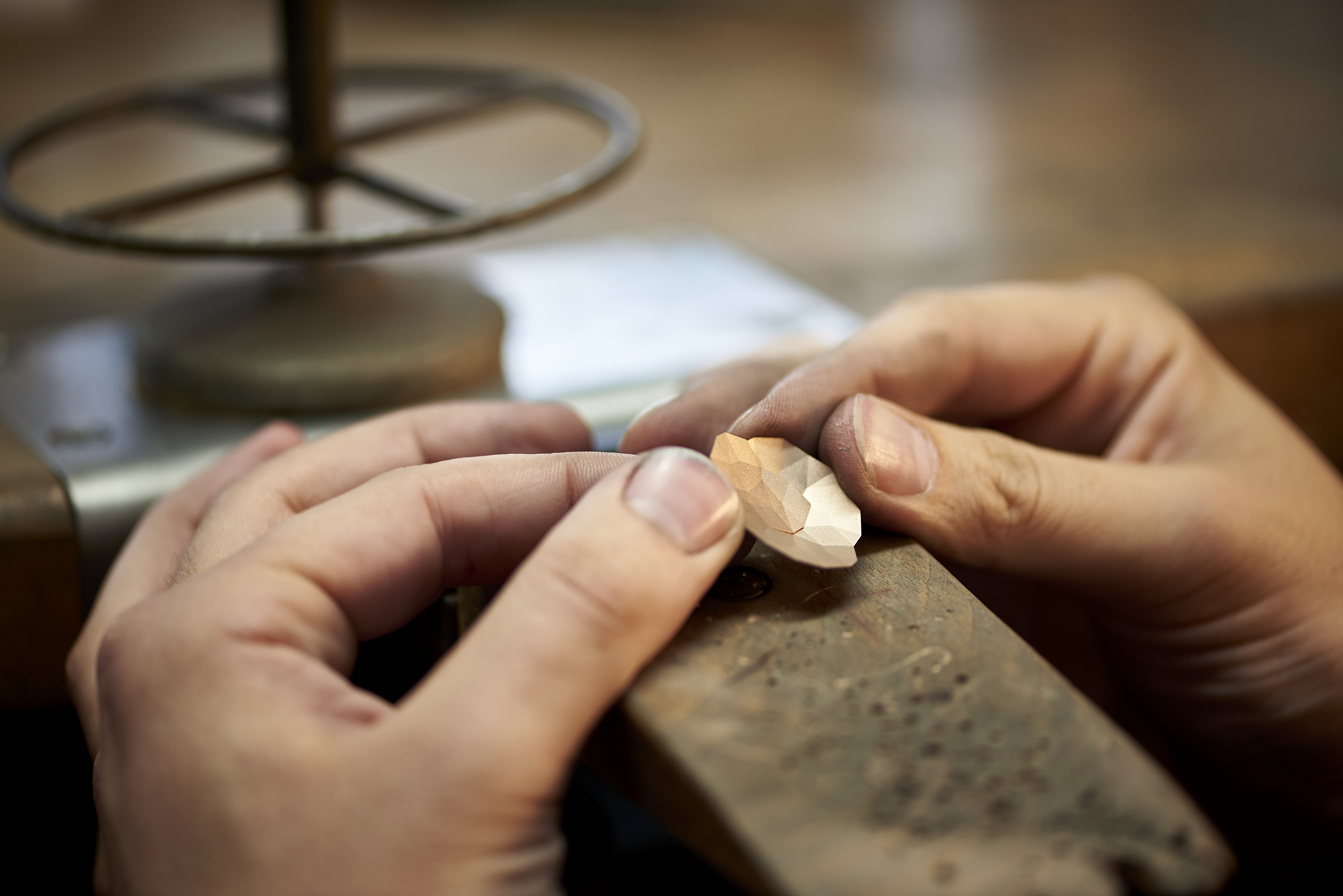 Die Hände eines Goldschmiedes halten ein Schmuckstück der Reihe "Topia" von Niessing.
