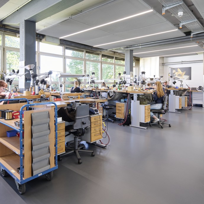 Mitarbeitende der Schmuckmanufaktur Niessing arbeiten an speziellen Arbeitstischen für das Goldschmiedehandwerk. (vergrößerte Bildansicht wird geöffnet)
