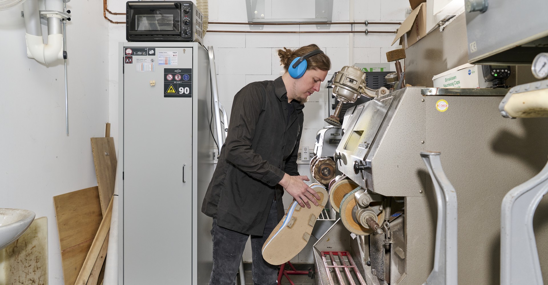 Adrian Wessels bearbeitet einen Schuh an einer Schleifmaschine.