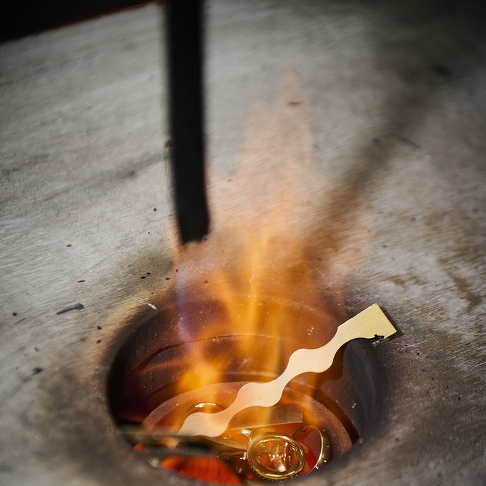 Goldteile liegen in einem Tiegel über einer Flamme. (vergrößerte Bildansicht wird geöffnet)