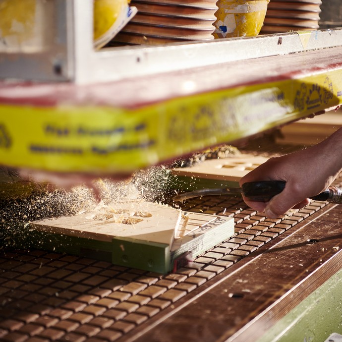 Mit einem Druckluftkompressor werden Holzspäne von einem Werkstück in der CNC-Fräse entfernt. (vergrößerte Bildansicht wird geöffnet)