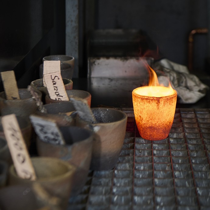 Ein glühender Tiegel steht auf einem Metallgitter. (vergrößerte Bildansicht wird geöffnet)