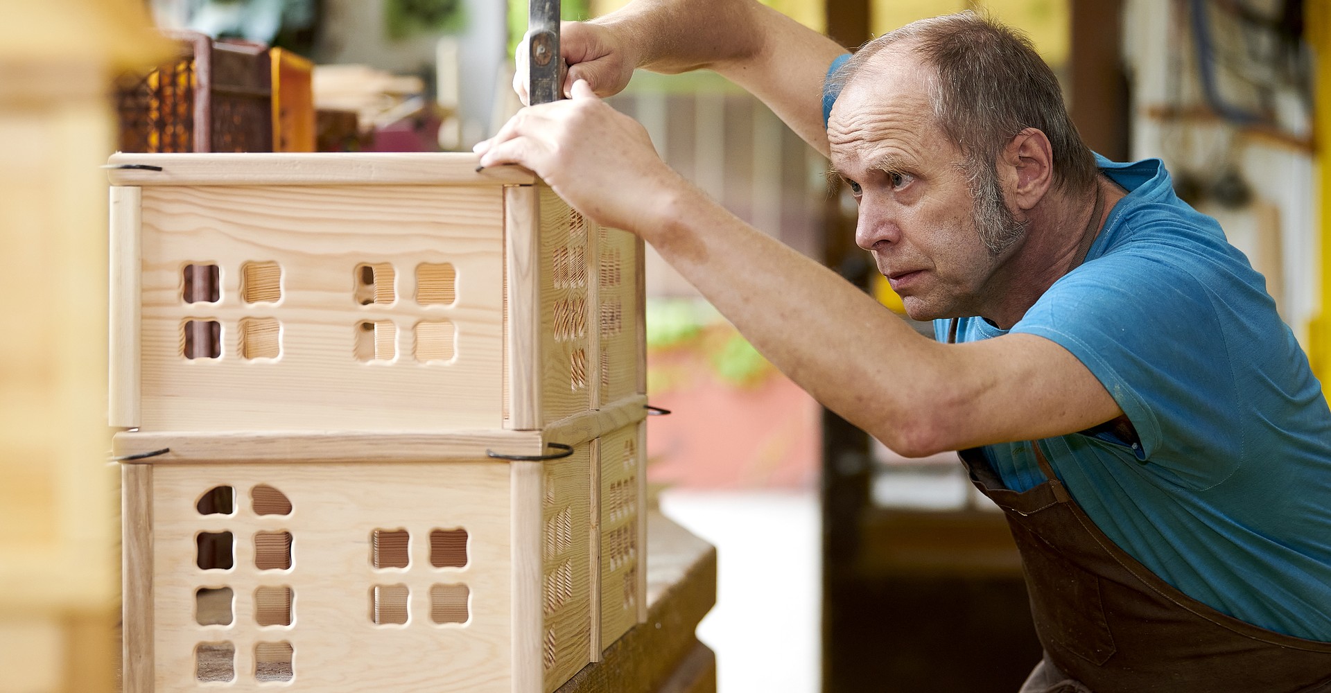Holzspielzeugmacher Norbert Stock bearbeitet ein hölzernes Puppenhaus.