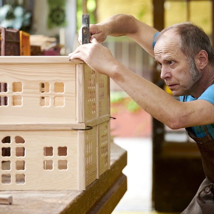 Holzspielzeugmacher Norbert Stock bearbeitet ein hölzernes Puppenhaus. (vergrößerte Bildansicht wird geöffnet)